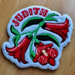 Alfombra flor copihue hecha a mano con diseño personalizado y flores rojas sobre fondo blanco.