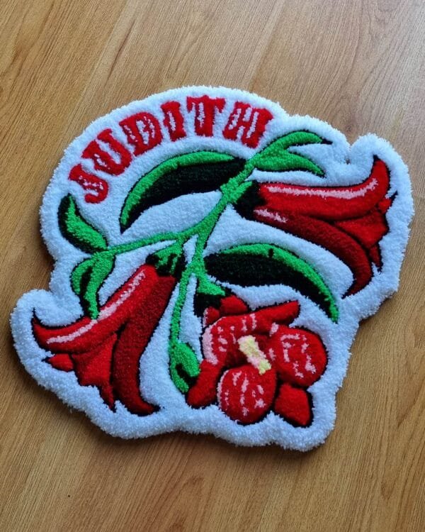 Alfombra flor copihue hecha a mano con diseño personalizado y flores rojas sobre fondo blanco.