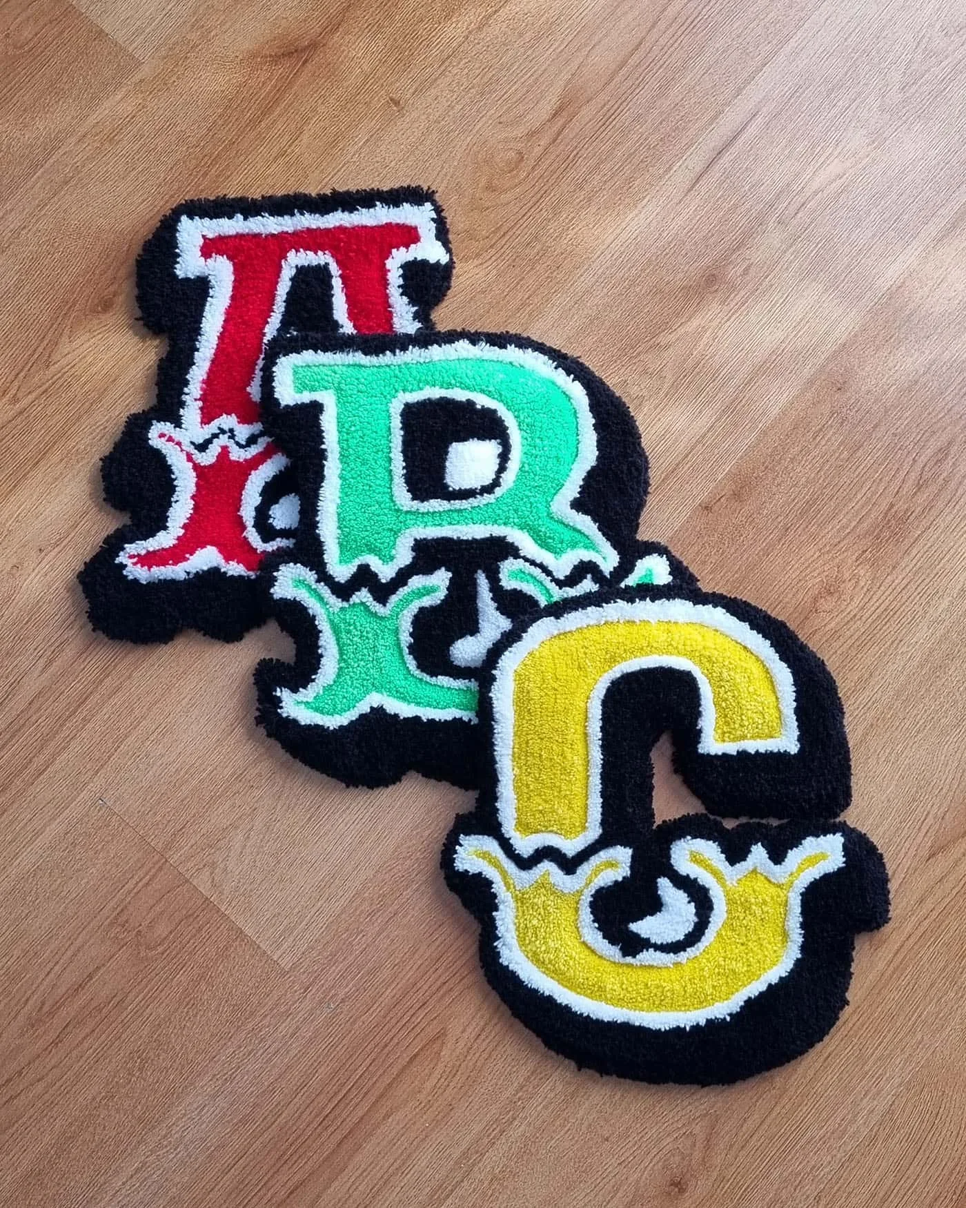 Conjunto de tres alfombras estilo infantil, cada una es una alfombra letra decorativa diferente.