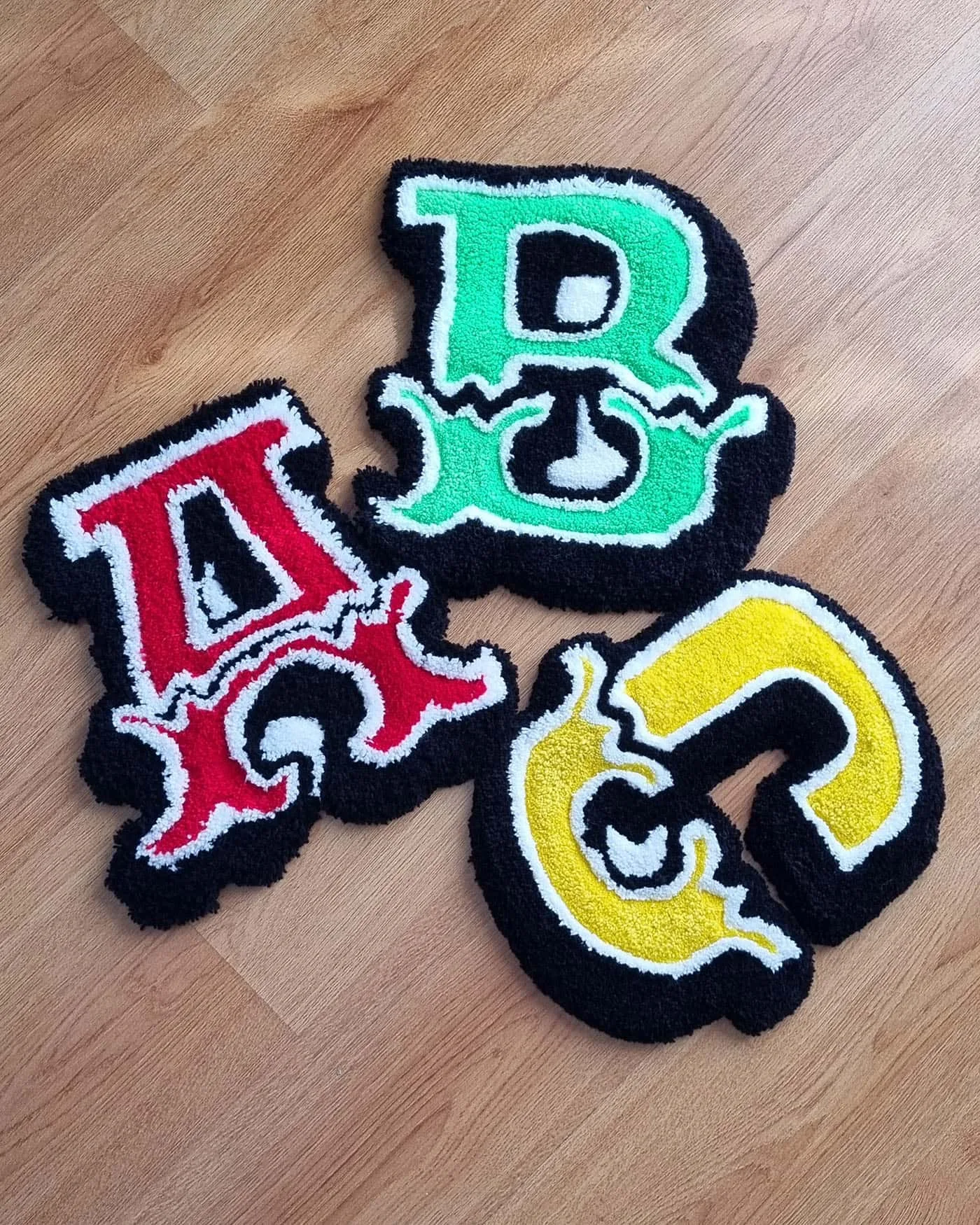 Composición de tres alfombras en forma de letra: cada alfombra letra decorativa representa una inicial diferente.