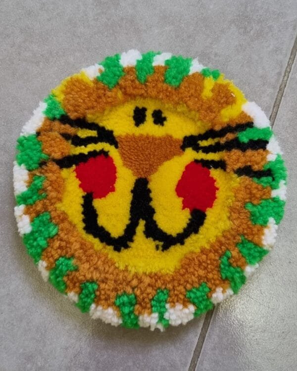 Alfombrita posavasos con diseño de león en estilo tierno y colores vivos.