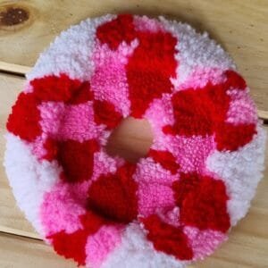 Alfombrita posavasos margarita hecha a mano con pétalos en tonos rosados y fondo blanco.