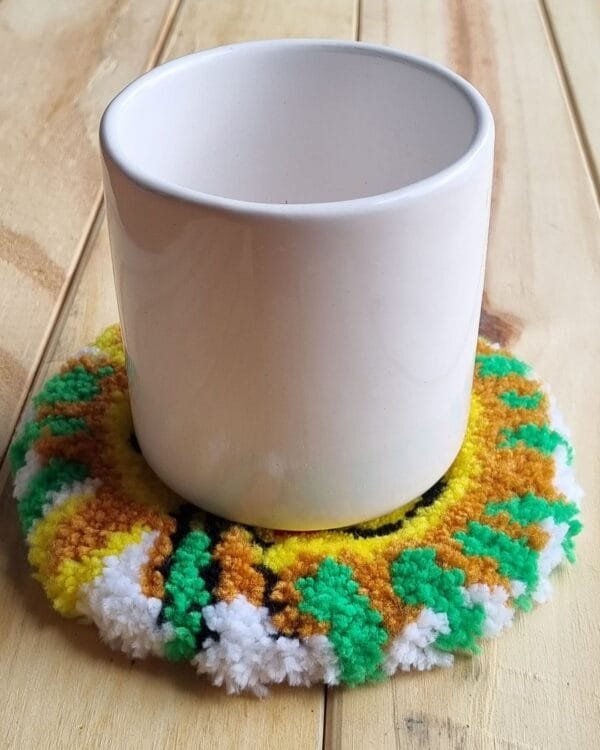 Alfombrita posavasos león con vaso, ejemplo de uso decorativo.